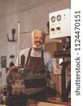 Smiling elderly man in uniform in a workshop