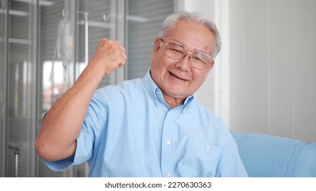 Smiling elderly patient Asian man flexing muscles and looking at camera feels healthy. Elderly healthcare concept. Showing biceps, muscles - Powered by Shutterstock