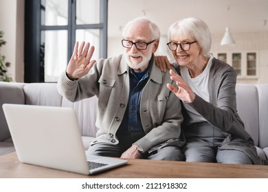 Smiling Elderly Senior Grandparents Couple Having Videocall Conference On Laptop Talking With Relatives, Grandchildren, Friends. Old Wife And Husband Communicating Online At Home Using Laptop.