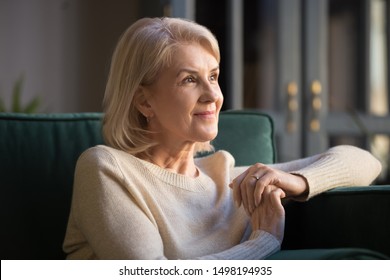 Smiling Elderly Woman Look In Distance Feel Cheerful Positive Remembering Good Old Days, Happy Mature Female Sit On Couch At Home Thinking, Enjoying Pleasant Memories, Recollecting Or Visualizing