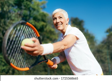 Smiling Elderly Woman Playing Tennis as a Recreational Activity - Powered by Shutterstock