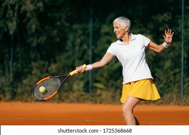 Smiling Elderly Woman Playing Tennis as a Recreational Activity - Powered by Shutterstock