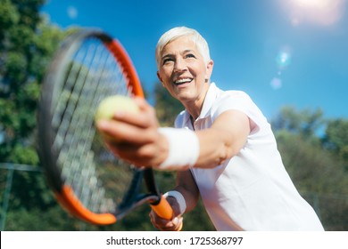 Smiling Elderly Woman Playing Tennis as a Recreational Activity - Powered by Shutterstock