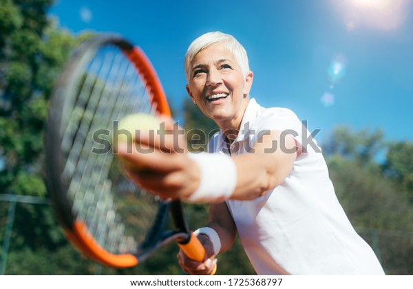 Smiling Elderly Woman Playing Tennis as a\
Recreational Activity