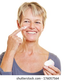 Smiling Elderly Woman Putting Skin Care Lotion On Her Face