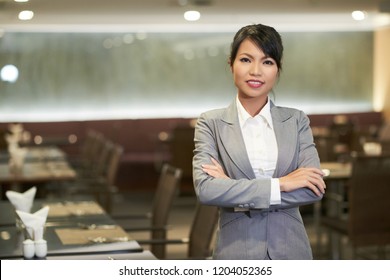 Smiling Elegant Asian Woman In Suit Working As Hostess In Hotel Restaurant Looking At Camera