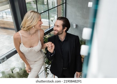 Smiling Elegant Couple Holding Hands In Restaurant