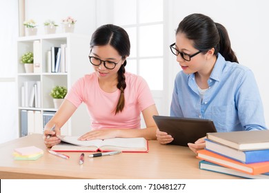 smiling elegant family teacher woman using mobile digital tablet to teach female student studying and preparing school exam. - Powered by Shutterstock