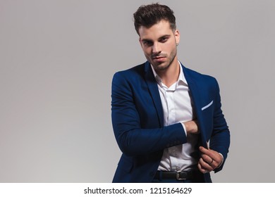 Smiling Elegant Man Searching In The Inside Pocket Of His Coat On Grey Background