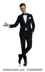 Smiling Elegant Man In Tuxedo Inviting And Presenting To Side, Standing Isolated On White Background, Full Body