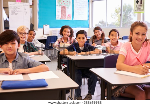 笑顔の小学生が教室で机に向かって座っている の写真素材 今すぐ編集