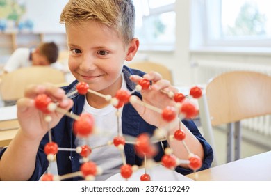 Smiling elementary schoolkid learning through molecular structure in class