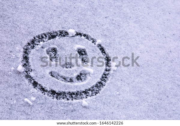 Smiling\
emoticon drawn on first snow on the\
windshield