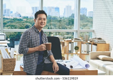 Smiling engineer having coffee break in architecture bureau