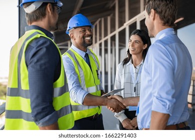 Smiling engineer shaking hands at construction site with happy architect. Handshake between african construction manager with businessman at bulding site. Team of workers conclude an agreement.