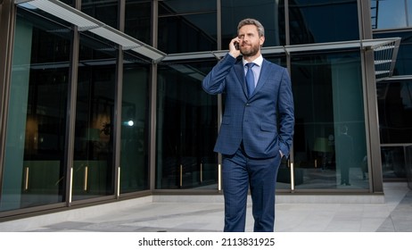 Smiling Entrepreneur In Businesslike Suit Has Phone Conversation Outside The Office, Business Call