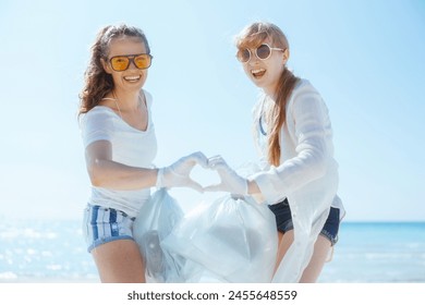 smiling environment activists on the beach with trash bags collecting garbage and showing heart shaped hands. - Powered by Shutterstock