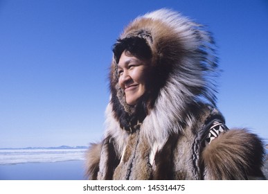 Smiling Eskimo woman wearing traditional clothing in wind against clear blue sky