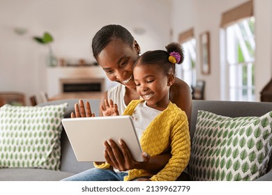 Smiling ethnic mother and funny daughter on video call using digital tablet at home. African american mature mother and little girl using digital tablet while making video call and waving hello. - Powered by Shutterstock