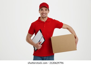 Smiling European Male Courier Hold Cardboard Box And Clipboard. Concept Of Shipping And Logistics. Young Man Wearing Uniform And Looking At Camera. Isolated On White Background In Studio. Copy Space