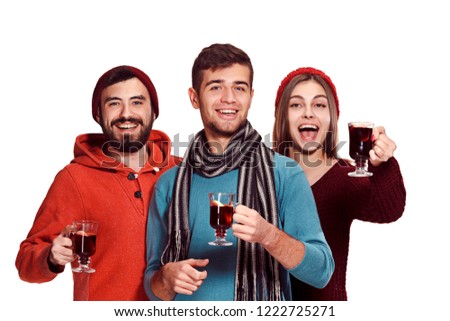 Smiling european men and women during party photoshoot. The guys posing as friends at studio fest with wineglasses with hot mulled wine on foreground.