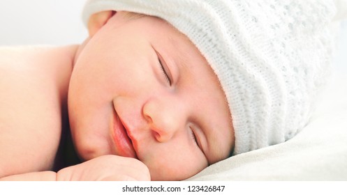 Smiling European Newborn Baby In White Hat