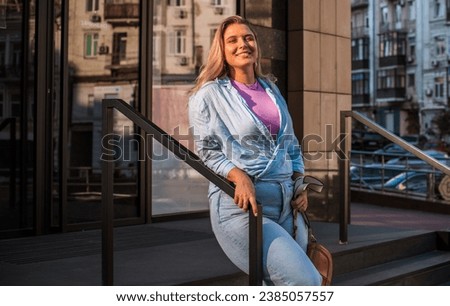 Smiling European plus size model in casual clothes, city behind her. Pretty nice chubby woman