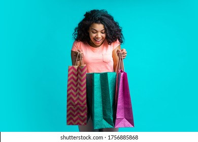 Smiling Excited Dark Skinned Girl Looking Into One Of The Shoping Bags She's Holding Checking Her Purchase.