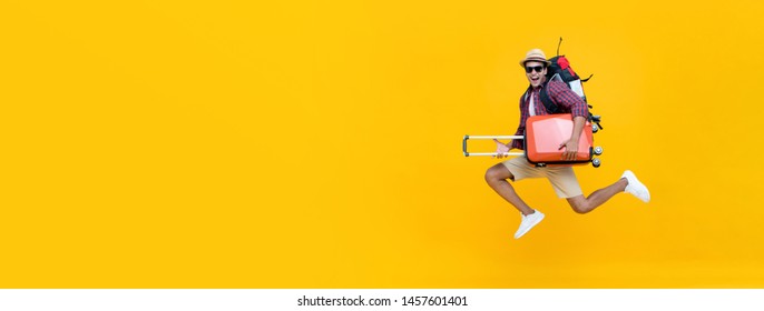 Smiling Excited Handsome Indian Tourist Man With Backpack Holding Baggage And Jumping Ready To Go For Travel Isolated On Yellow Banner Background With Copy Space