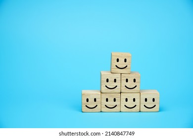 Smiling face icons on wooden cubes. Business service rating, customer satisfaction or teamwork concept. on blue background.                        
