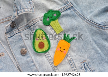 Smiling face kawaii style brooches made from felt fabric, on jeans jacket.