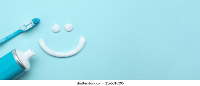Smiling face made of toothpaste, brush and tube on light blue background, flat lay with space for text. Banner design