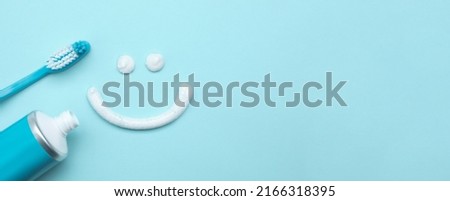 Smiling face made of toothpaste, brush and tube on light blue background, flat lay with space for text. Banner design