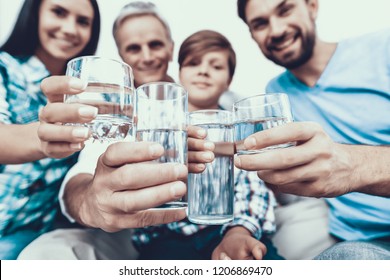 Família sorridente bebendo água em copos em casa. Pai e filho. Pessoas sorridentes. Conceito de paternidade. Família em casa. Família feliz. Copo de água. Jovem mulher. Família na sala de jantar.