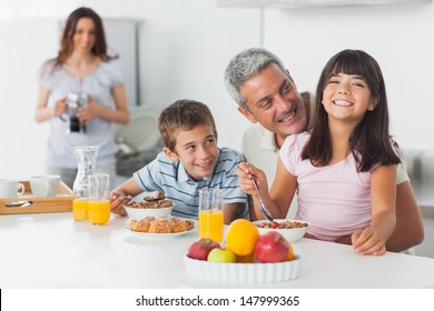 Smiling Family Eating Breakfast In Kitchen Together At Home