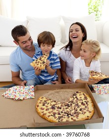 Smiling Family Eating Pizza On Sofa At Home