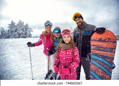 Smiling Family Enjoying Winter Sports And Vacation On Snow In Mountains