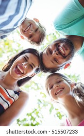 Smiling Family Forming Huddle Against Sky