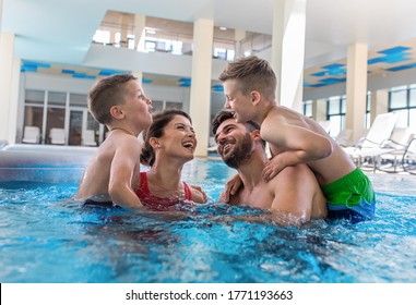 Smiling family of four having fun and relaxing in indoor swimming pool at hotel resort. - Shutterstock ID 1771193663