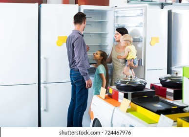 Smiling Family Of Four Shopping New Refrigerator In Home Appliance Store 
