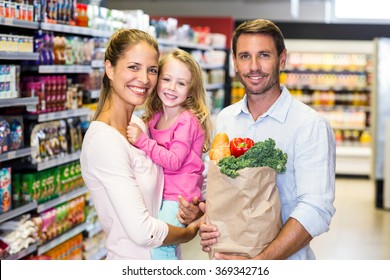 Smiling Family With Grocery Bag At The Supermarket Posing For Camera