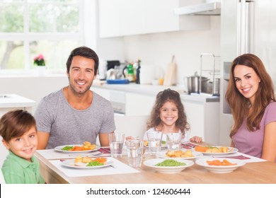 Smiling Family Having Dinner In Kitchen