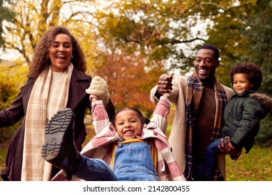 Smiling Family Having Fun Swinging Daughter On Walk Through Countryside Against Autumn Trees - Powered by Shutterstock