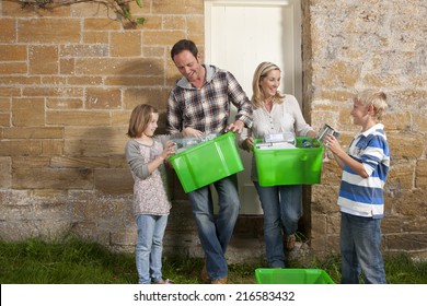 Smiling Family Holding Bins Full Of Recycling Materials