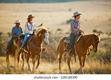 Smiling Family Horseback Riding On A Ranch.