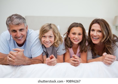 Smiling Family Laying On The Bed Together