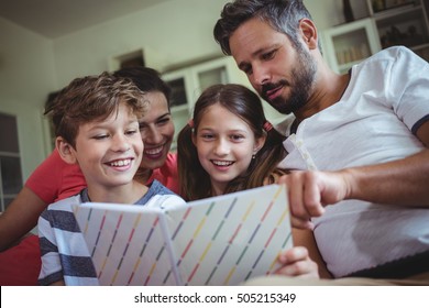 Smiling Family Looking At A Photo Album At Home