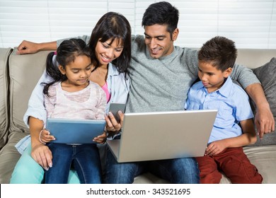 Smiling Family On The Sofa Using Technology