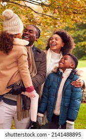 Smiling Family On Walk Through Countryside Against Autumn Trees