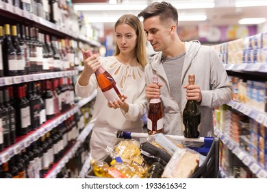 Smiling Family Pair Deciding What Wine To Buy In Grocery Store